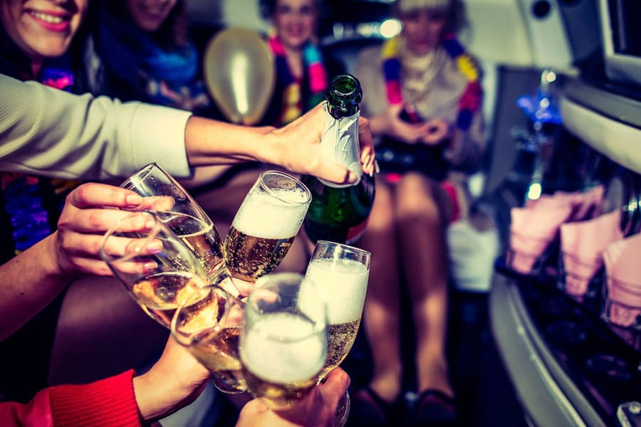 Glasses filled with Champagne and people enjoying in background in a party organised by Metrowest Limousine